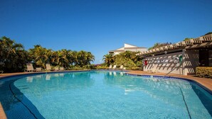 Una piscina con tumbonas y palmeras.