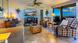 Un salón amplio con televisor grande, asientos cómodos y un balcón con vistas.