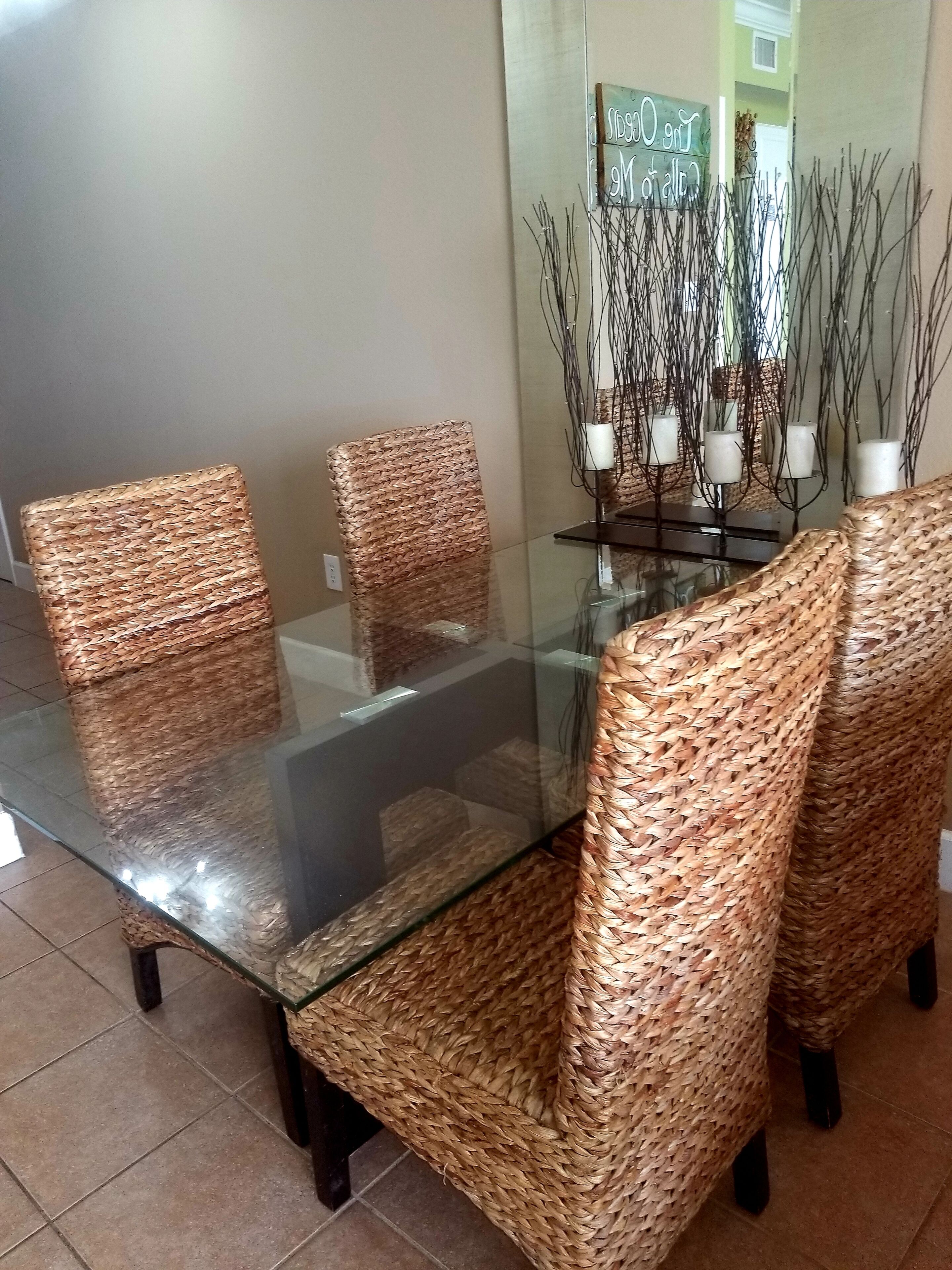 A dining area with a glass-top table surrounded by woven chairs.