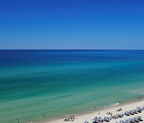 A beach with clear turquoise water, a sandy shore, and several beach umbrellas.