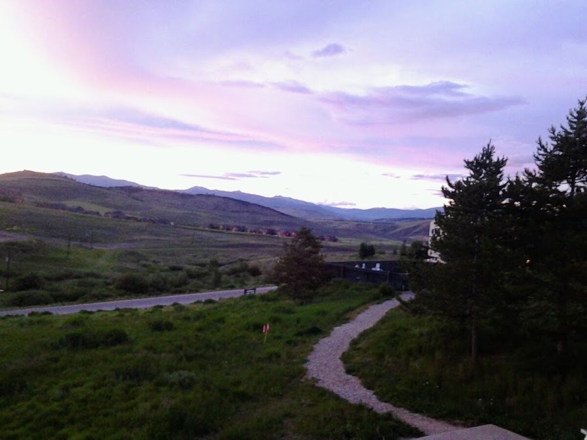 A rural landscape with a winding road, a small building, and distant hills.