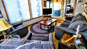 A living room with a sofa, armchairs, a coffee table, and a television.