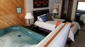 A hotel room with a bed, a nightstand, a lamp, a painting, and a jacuzzi.