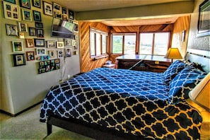 Une chambre à coucher avec un lit, un bureau et un téléviseur fixé au mur.