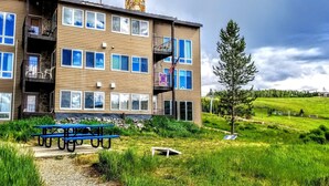 A multi-story building with balconies, a barbecue grill, and a picnic table in the foreground.