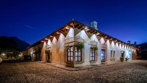 A building with a stone facade, multiple windows with metal grilles, and a cobblestone street. - Unique Central & Beautiful home (views to die for from Balcony!) (Antigua Guatemala)