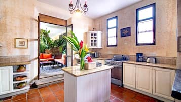 Una cocina con una isla central, armarios blancos, estufa y cafetera.