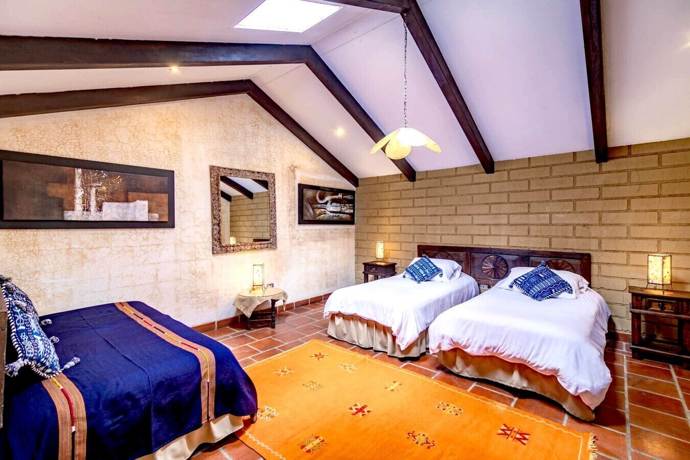 Un dormitorio con dos camas, un espejo grande y una lámpara colgante.