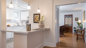 A modern kitchen with white cabinetry, pendant lighting, and a central island.