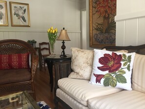 Un soggiorno con un divano, poltrone, un tavolino con una lampada e un vaso di fiori.