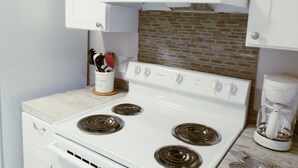 A kitchen with a white stove, a coffee maker, and a utensil holder. - Tarpon Qtrs! 1BR/1BA w/Dog Friendly Fenced Yard, Walk to the Beach! (Port Aransas)