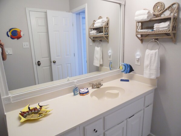 A bathroom with a white sink, a mirror, and a towel rack. There is a door in the background.