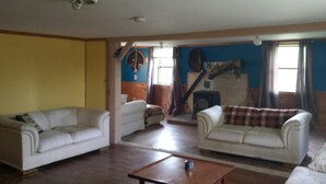 Un salón con dos sofás blancos, una mesa de centro de madera y una pared azul con un mural.