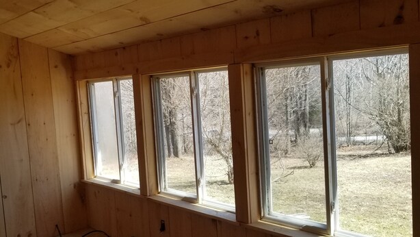 Una habitación con paredes de madera y un ventanal que da a un patio.