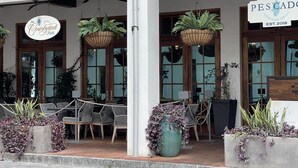 En restaurant med udendørs siddepladser, hængende planter og et skilt, der angiver, at det er en fiskerestaurant.