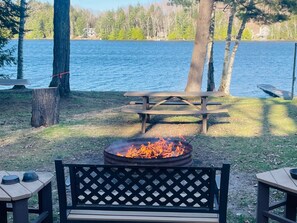 A lakeside picnic area with a fire pit, picnic table, and benches. - Lakefront Cabin, Pet Friendly, WIFI , near Pictured Rocks Munising Mi. (Wetmore)
