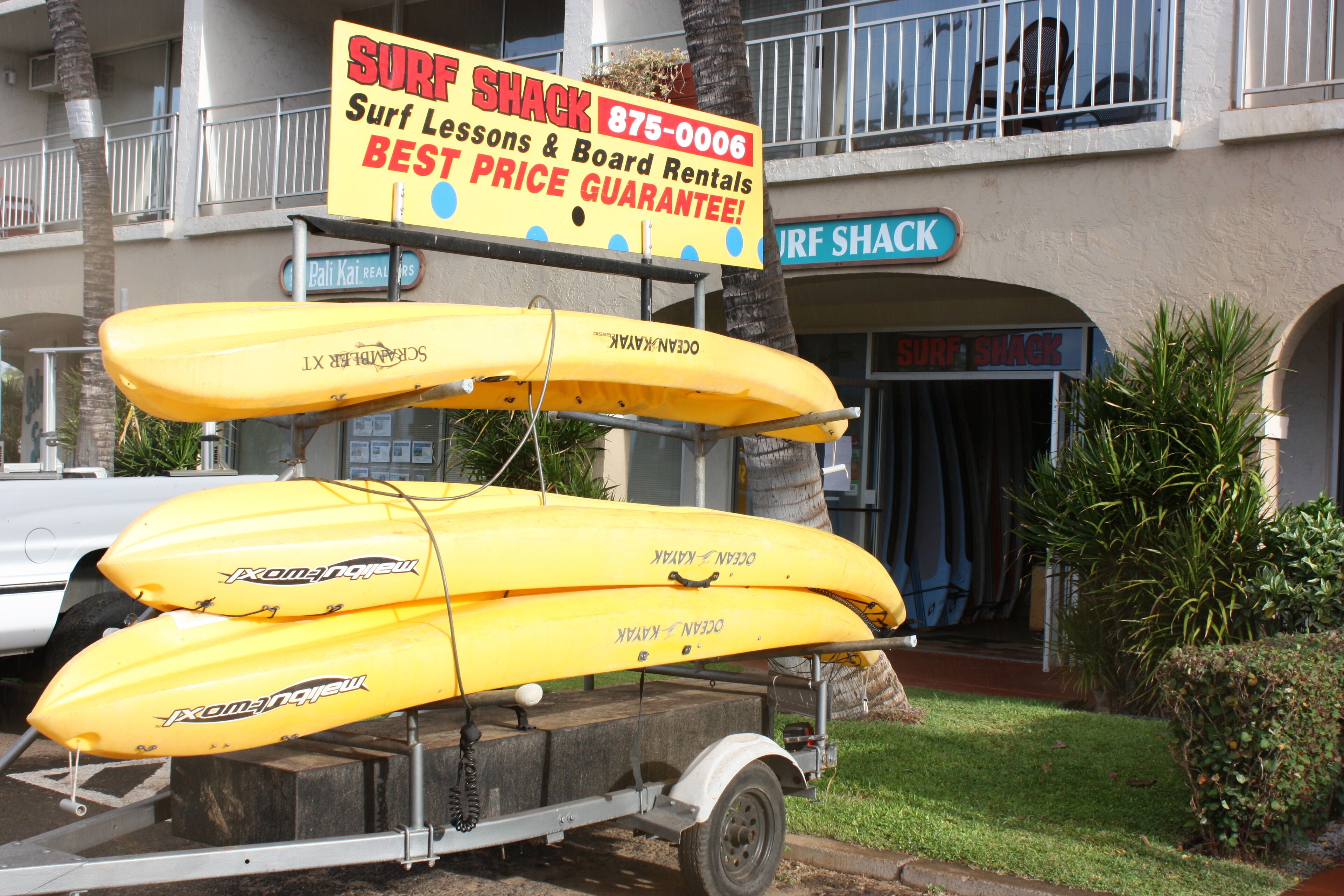 Una cabaña para surfistas con un letrero que anuncia clases de surf y alquiler de tablas.