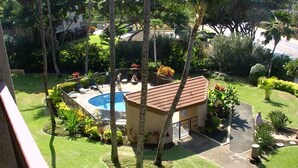Ein Wohngebiet mit Swimmingpool, Palmen und einem kleinen Gebäude mit Ziegeldach.