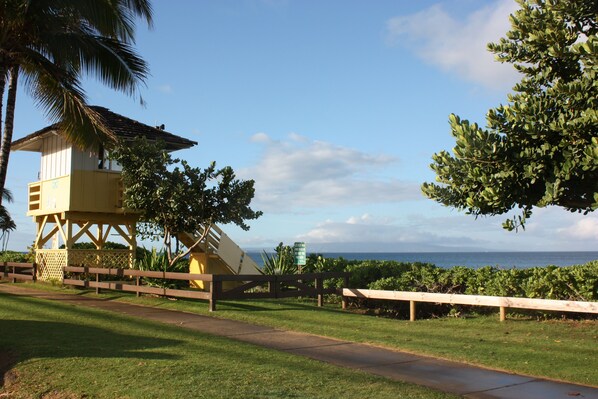 A lifeguard tower, a wooden fence, and a bench by the ocean.
