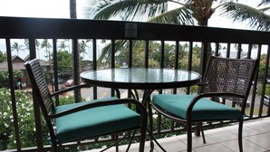 Ein Balkon mit zwei Korbstühlen und einem kleinen runden Tisch.