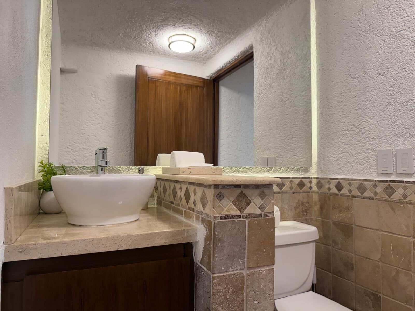 Une salle de bain avec un grand lavabo blanc, une porte en bois et un mur recouvert de carreaux.