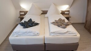 Habitación doble con dos camas individuales, cada una con una almohada y una mesita de noche.