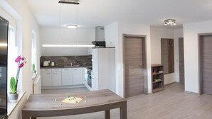 Una cocina moderna con gabinetes blancos, salpicadero de piedra y horno empotrado.
