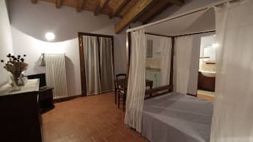 A bedroom with a bed, a wooden ceiling, a radiator, a desk, and a chair.