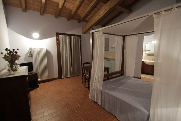 Ein Schlafzimmer mit Bett, Holzboden, Heizkörper, Schreibtisch und Stuhl.