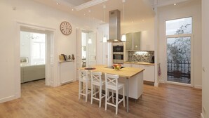 A spacious kitchen with a central island, white cabinetry, and a large window offering a view of the outdoors. - Large 3BR/3BA Flat Next to Central Market | Free Parking (Budapest)