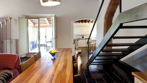 Un espacio habitable amplio con una mesa de comedor de madera, un sofá rojo y una escalera que lleva a un piso superior.