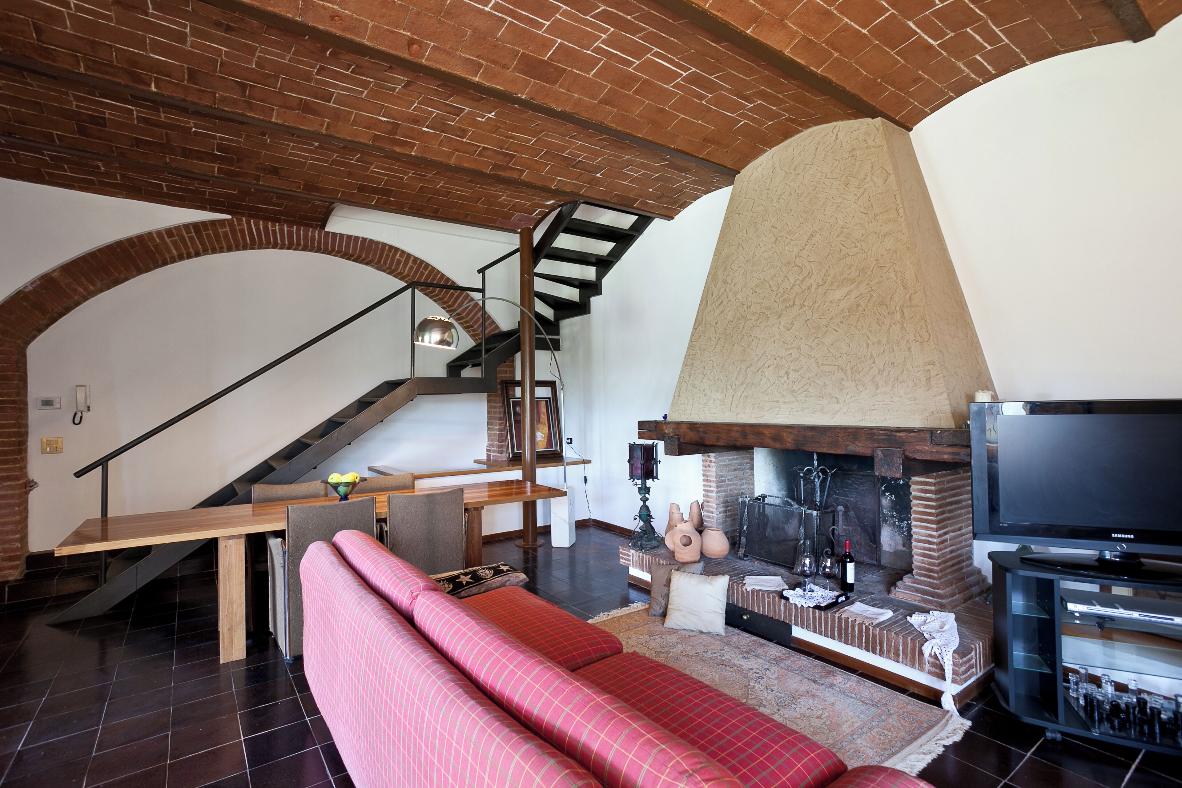 Un salon moderne avec une cheminée, un canapé, un téléviseur et un escalier.