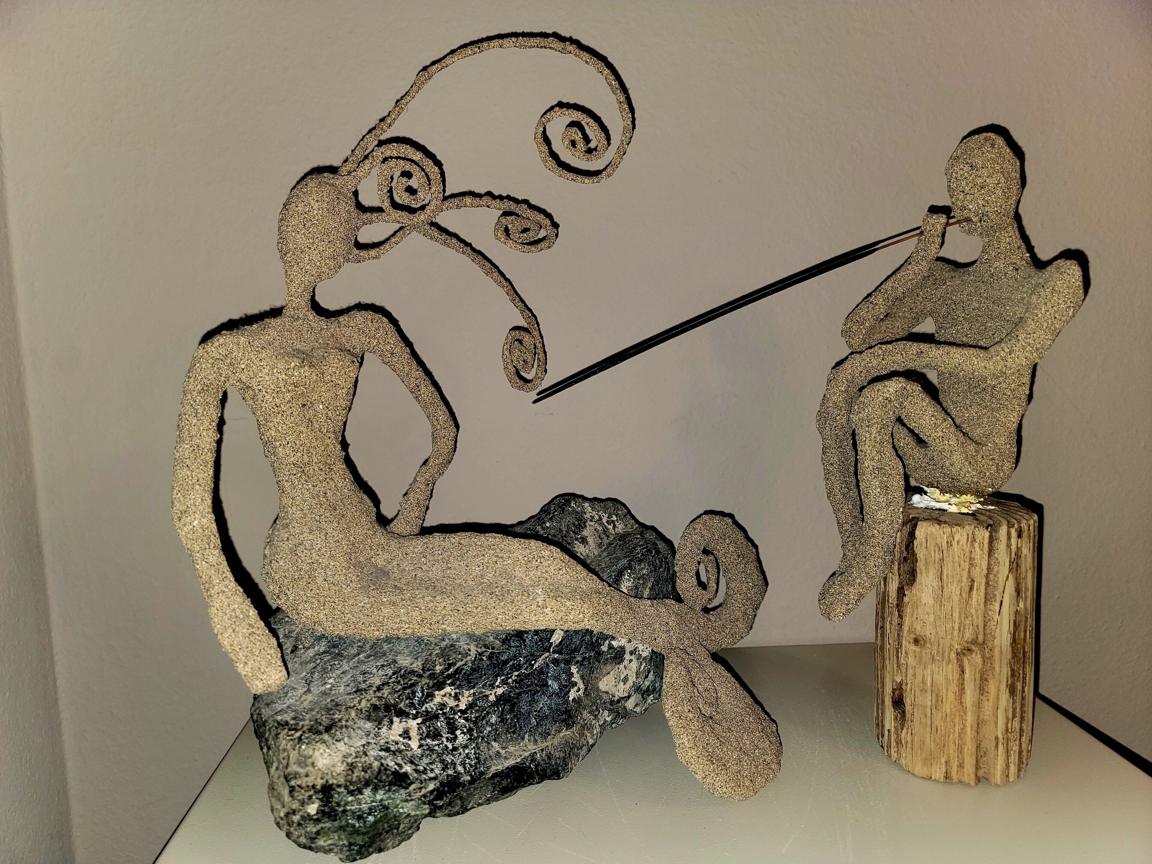 A sculpture of two abstract figures, one seated and one standing, connected by a line.