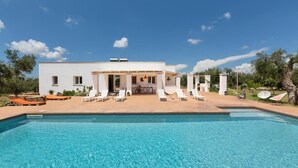 Una casa moderna con piscina, mobiliario exterior y zona de patio.