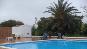 A swimming pool with two lounge chairs and a palm tree. - Magnificent house in Roses with pool and tennis. In Puigrom area of ​​Roses (Roses)
