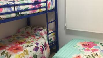 Ein Stockbett mit Blumenmuster-Bettwäsche und ein Einzelbett mit floralem Überwurf.