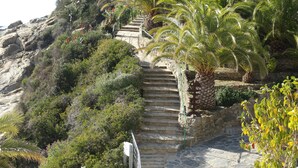 A stone staircase leading up a hill with palm trees and shrubs. - Magnificent house in Roses with pool and tennis. In Puigrom area of ​​Roses (Roses)