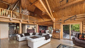 A spacious log cabin interior with a large living area, a dining area, and a kitchen.