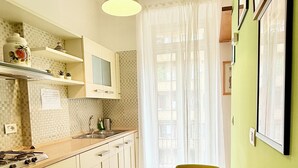 Een keuken met een fornuis, spoelbak en een eettafel met stoelen.