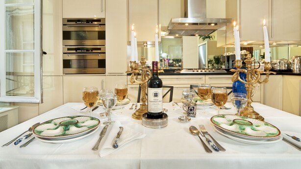 Una tavola da pranzo formale apparecchiata con piatti, bicchieri, posate, una bottiglia di vino e candelabri.