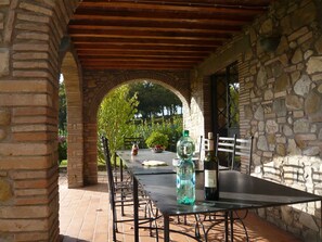 Une terrasse extérieure avec une table et des chaises, un mur en pierre et une vue sur la verdure.