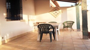 Un patio couvert avec une table et des chaises, une décoration murale et une fenêtre grillagée.