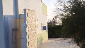 Un bâtiment doté d’une allée dallée, d’un mur en pierre et d’un pommeau de douche en métal.