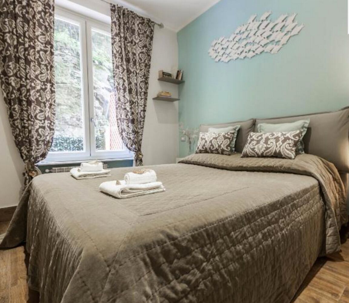Ein Schlafzimmer mit einem großen Bett, gemusterten Vorhängen, einem Fenster mit Blick und einer Wanddekoration.