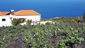 A white building with a red-tiled roof, a satellite dish, and a view of the ocean.