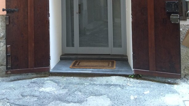 A building entrance with a wooden door, a small window with metal bars, and a number '15' on the wall. - The ancient alley, just a step away from everything (Salerno)