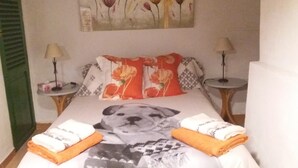A neatly made bed with a dog print bedspread, two pillows with floral designs, and a painting of flowers on the wall. - TOWN HOUSE SÓLLER CENTER - ETV13701 (soller)