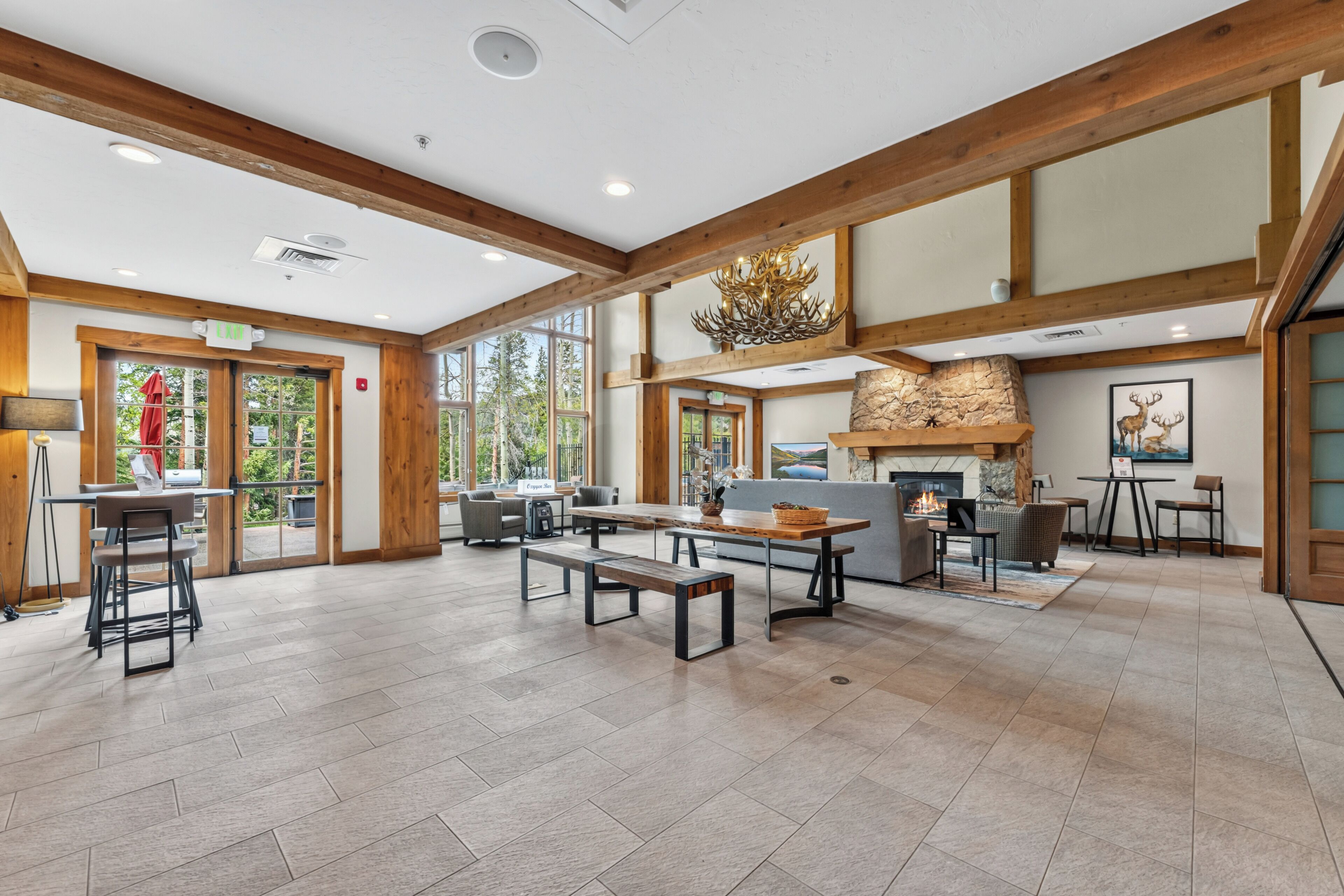 Un vaste espace intérieur doté d’une cheminée, de poutres en bois et de grandes fenêtres.