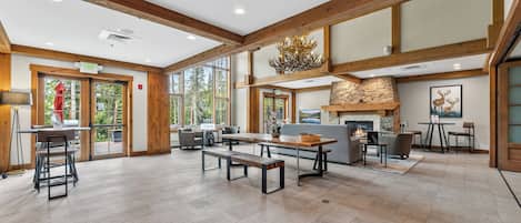 Un vaste espace intérieur doté d’une cheminée, de poutres en bois et de grandes fenêtres.