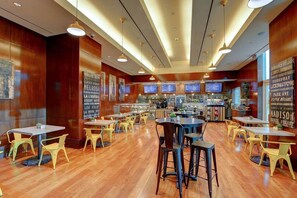 A spacious restaurant with wooden floors, yellow chairs, and multiple tables.
